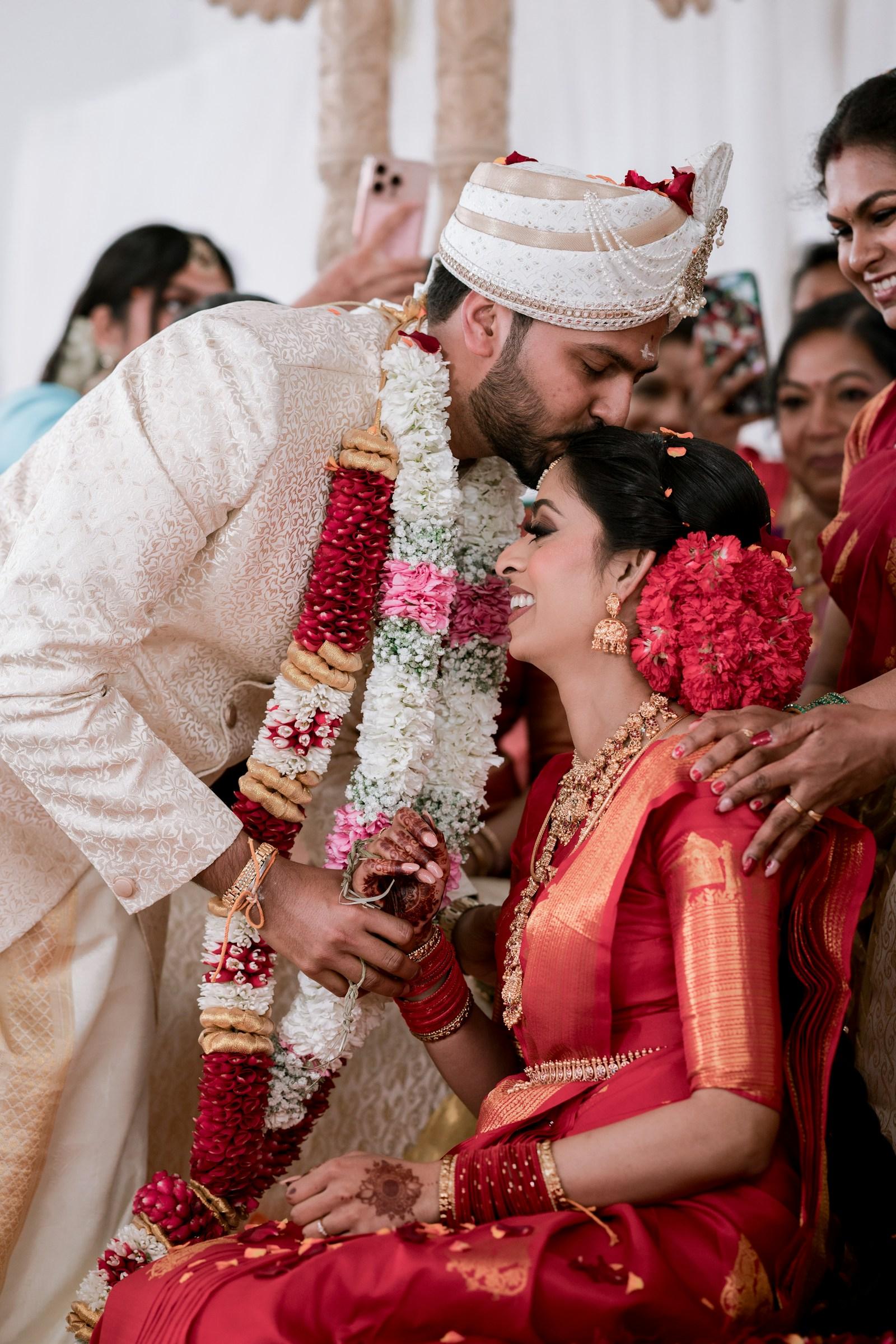Garlands exchanged — a groom kisses his bride’s forehead at the varmala moment