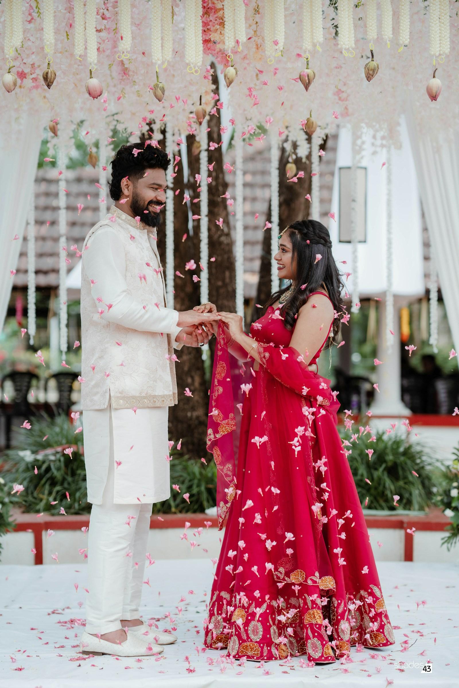 Rose petals falling as a couple exchanges rings under a floral canopy
