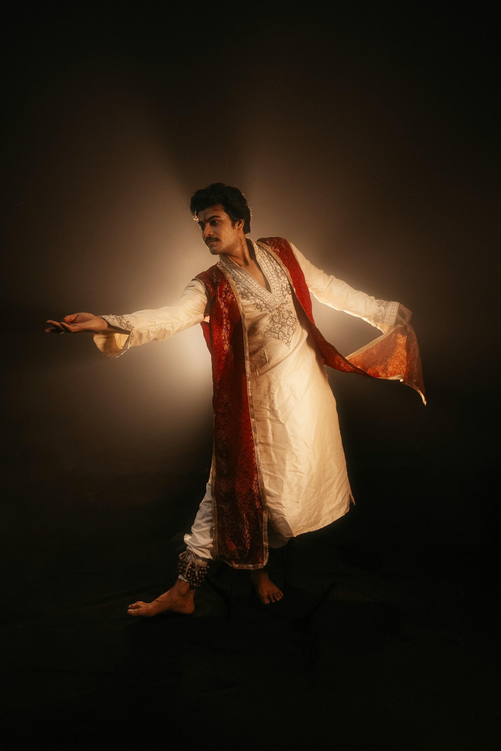 A kathak dancer mid-turn in cream and red, lit like candlelight